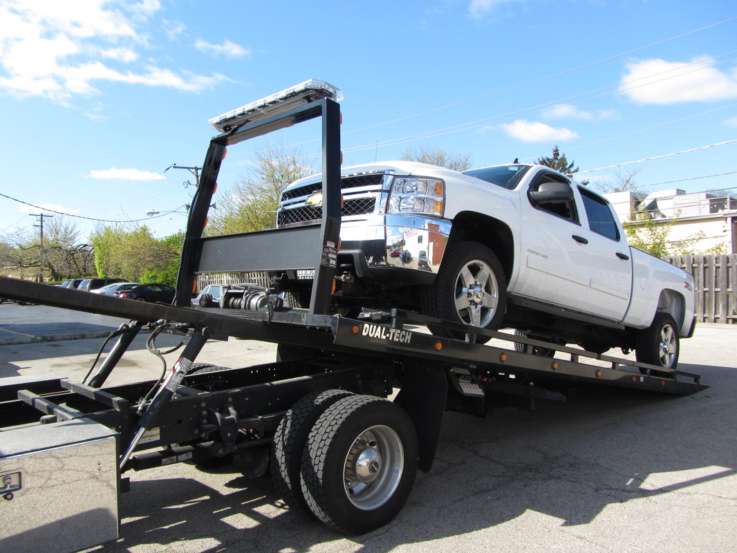Anthony's Towing flatbed loading a white pickup truck